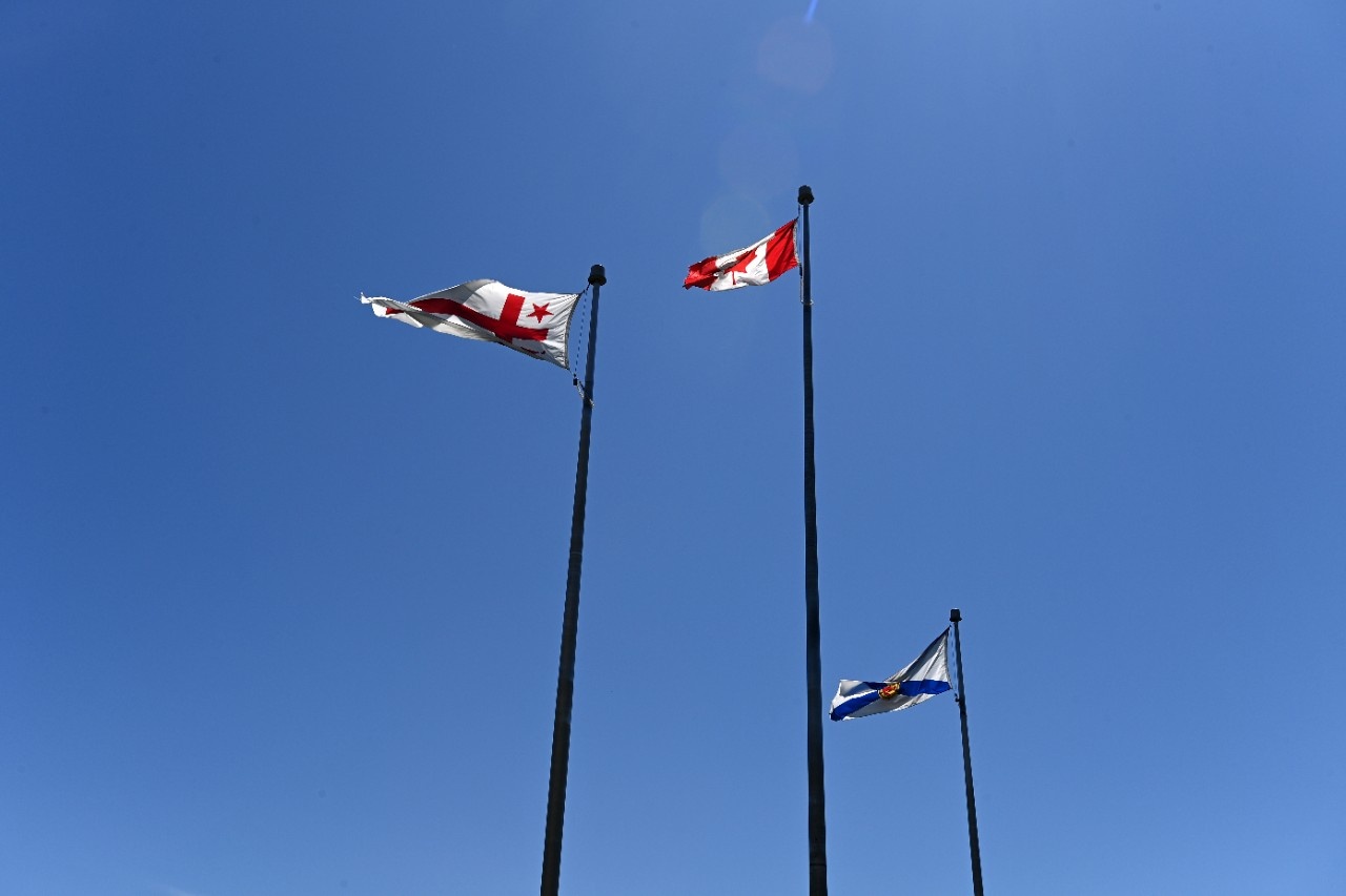 three flags on the flagpole with a clear blue sky