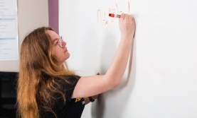 Student writing and equation on a whiteboard