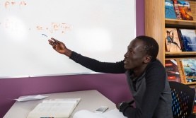 Student pointing at an equation written on a whiteboard