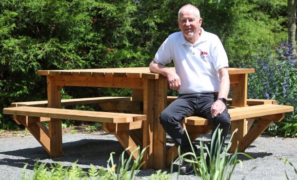 Dwight Higgins sits at the new picnic table donated to the Alumni Gardens by the Class of 1964.