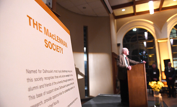 The MacLennan Society sign and Rod MacLennan at podium