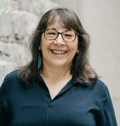 Sherry Pictou smiles at the camera in front of a stone wall.