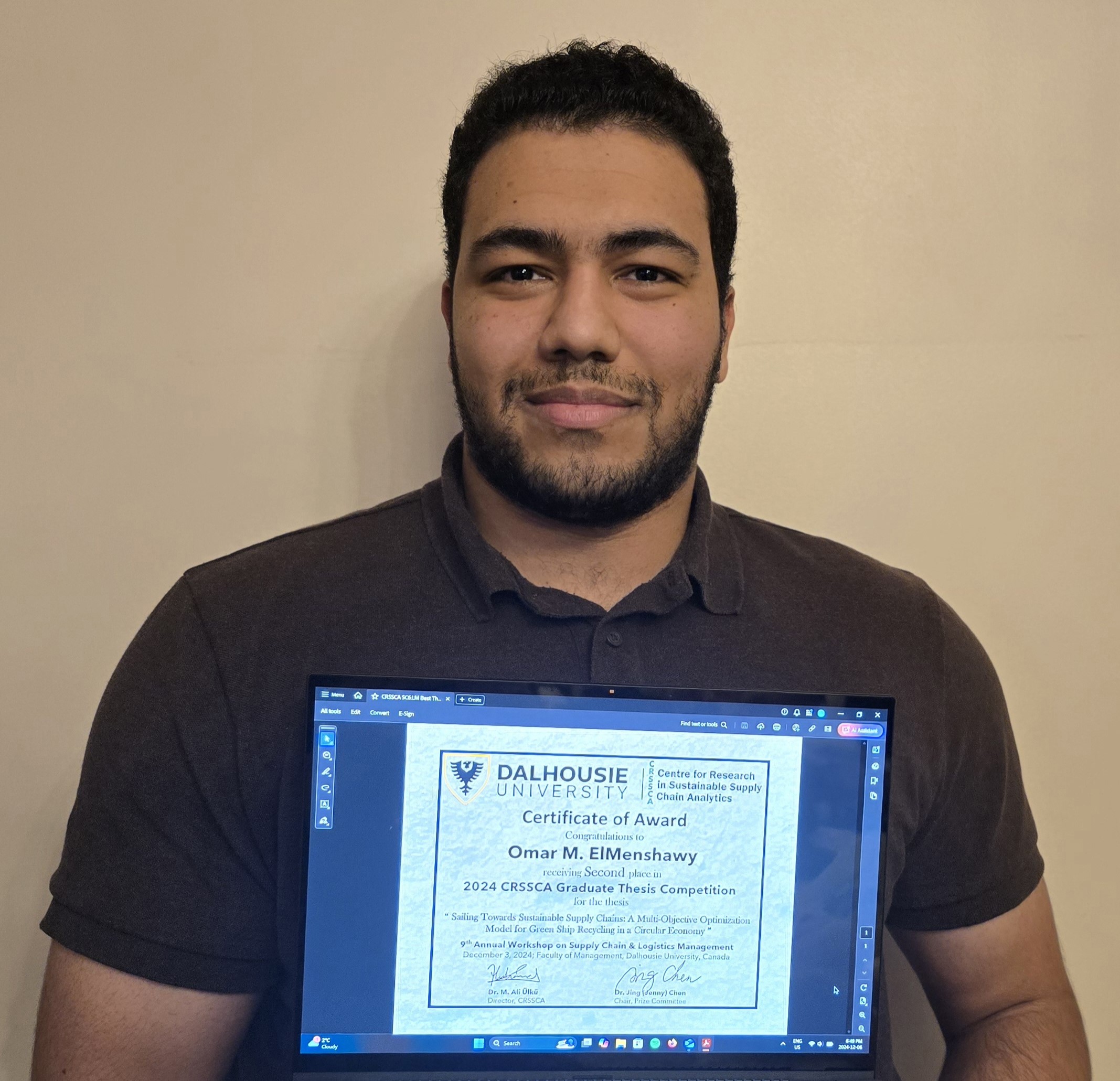 Omar stands, holding a certiicate, smiling. 