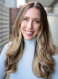 A photo of Christine Szarmes wearing a blue turtleneck, smiling at the camera.