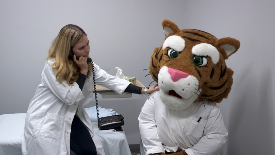 Professor consoling injured tiger mascot while talking on telephone