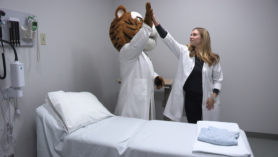 Tiger mascot and professor congratulating each other after making bed