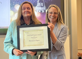 Marianne Hagen and Anna Cranston hold Marianne's award certificate between them, smiling at the camera. 