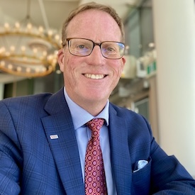 Chris Steeves, wearing a blue suit, smiles for the camera.