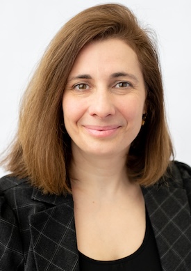 Headshot of Jane wearing an argyle-patterned blazer, smiling.