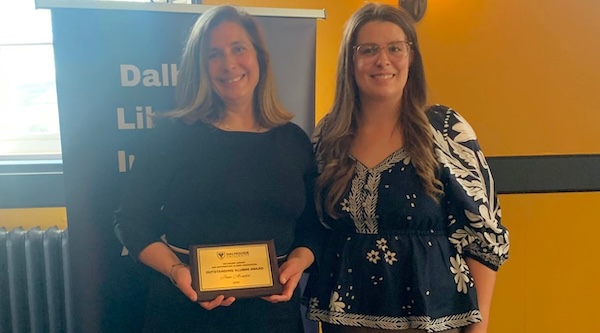 Jane poses with her award plaque next to a fellow alum.