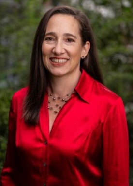 Lilia, smiling and wearing a bright red blouse.