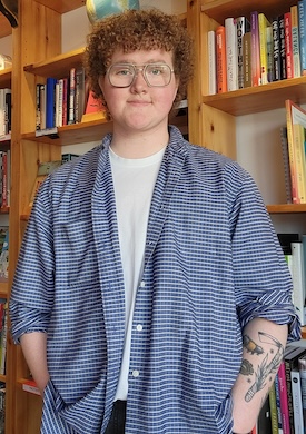 Rowan poses confidently in front of a bookcase.