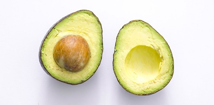 An avocado split into two halves.