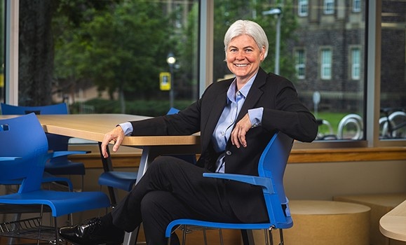 Dr. Kim Brooks seated in a blue chair in the Wallace McCain Learning Commons.