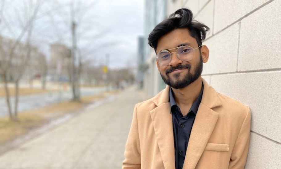 Anik Ahmed, wearing a light brown jacket, leans against a building at Dalhousie.