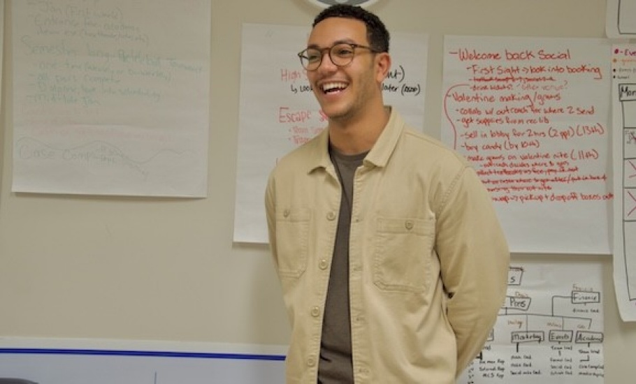 Mohammed poses in front of a board of handwritten notes.