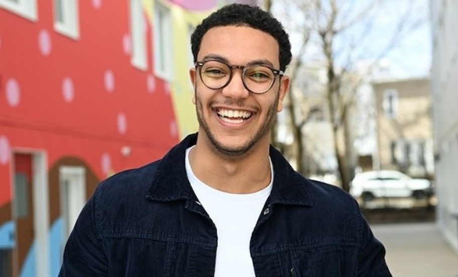 Mohammed poses in front of a board of handwritten notes.