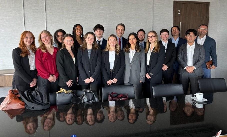 A group of students in business wear pose in a boardroom.
