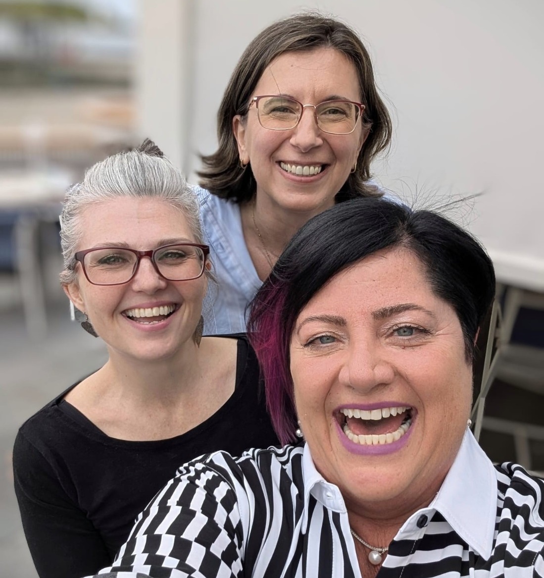 Selfie of Maria, Michele and Carrie dressed in busines casual clothing, smiling.