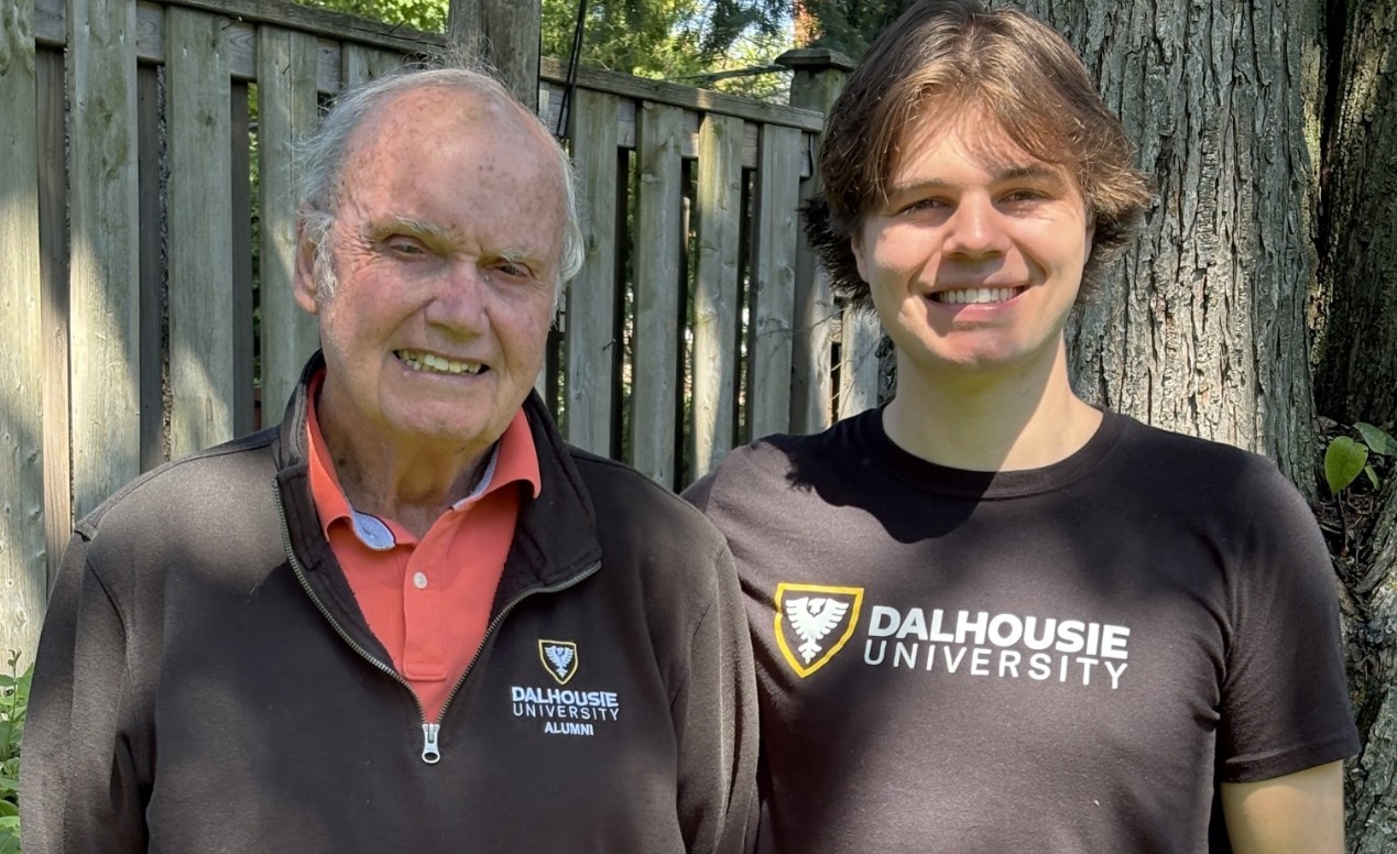Gil, left, in a ��ɫֱ�� alumni sweatshirt, and Ben in a ��ɫֱ�� t-shirt, posing outdoors and smiling.
