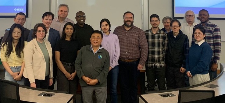 A group of students and faculty pose in a classroom with speaker Andy Chen at the centre.