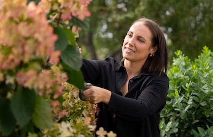 Geena working in a vinyard, tending to a flowering plant.