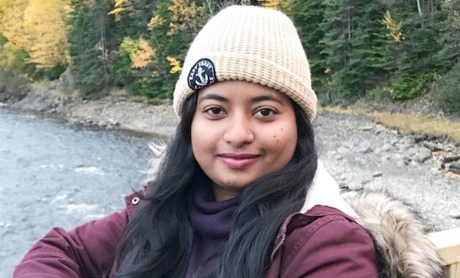 MES student Farzana Karim smiles at the camera. A lake and trees are in the background.