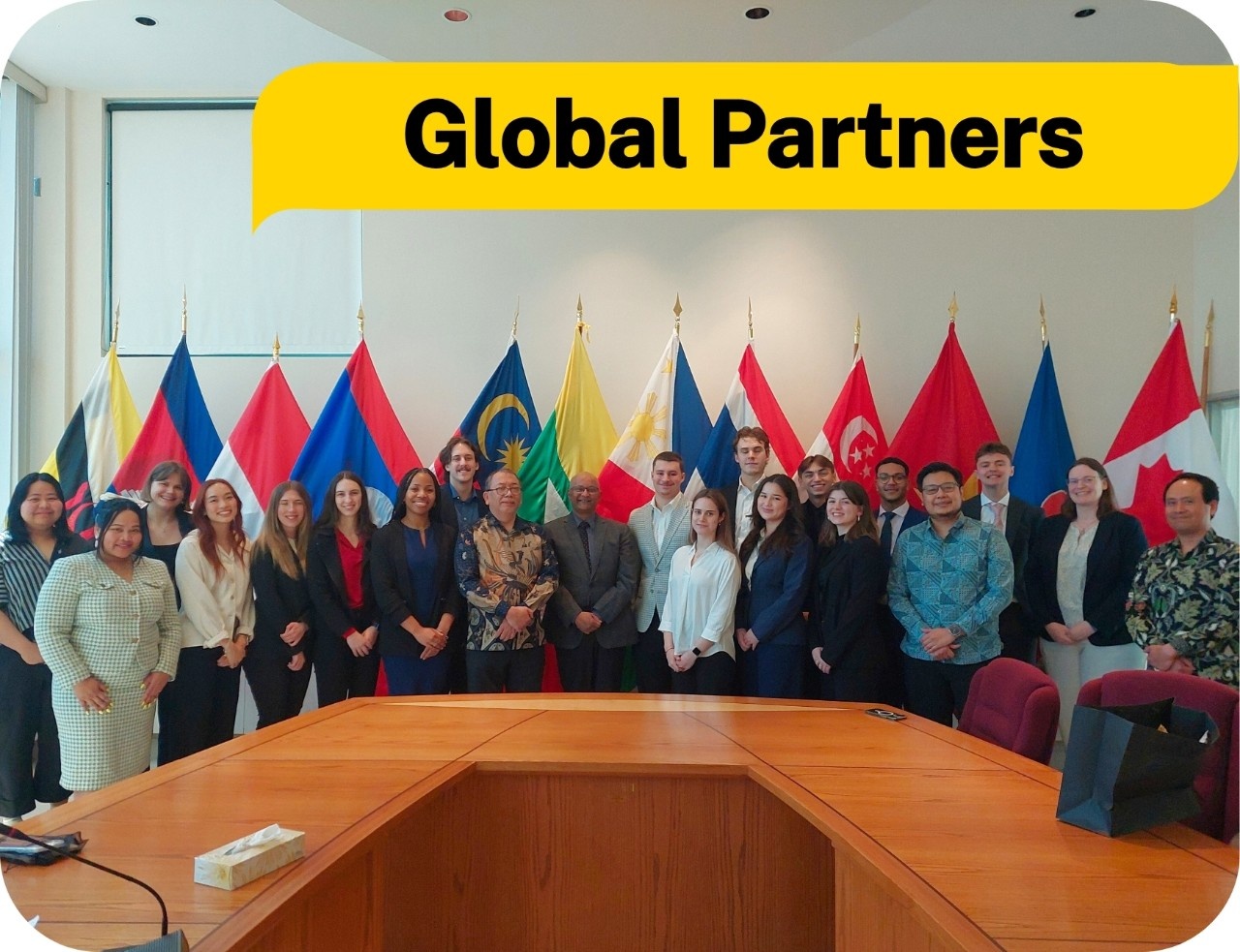 A group of people at a boardroom table with flags behind them. Text: Global partners.