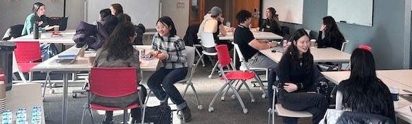 Students sit at tables in animated conversation.