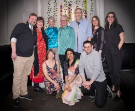 A group of College of Sustainability faculty and staff members pose together in front of an ivory curtain and colourful flower and vine decorations at the Green Gala.