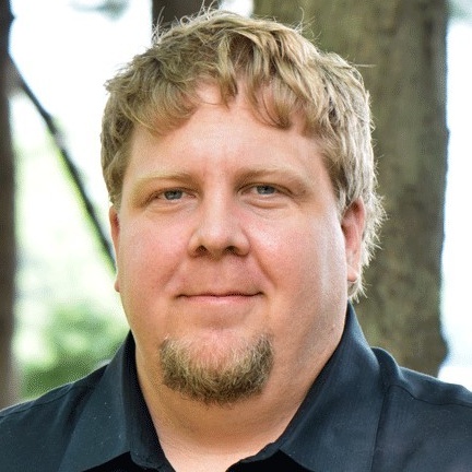 Nathan smiles. He has a light skin tone; short, light brown hair; and a small goatee.