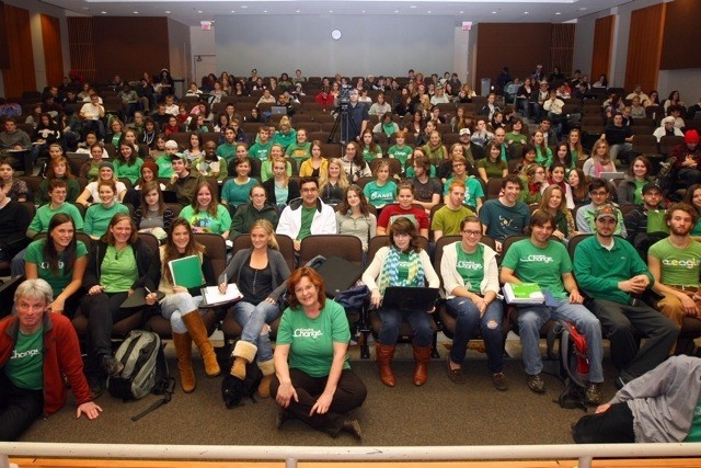 Group photo of 80-100 students in Ondaatje Auditorium wearing green "Leading Change" t-shirts.