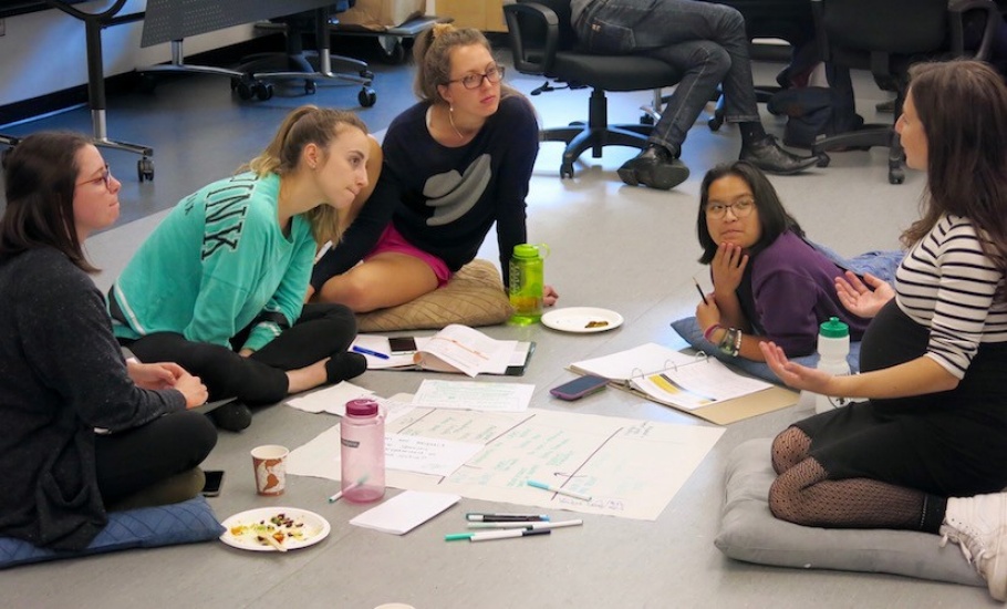 A group of students sit in a small circle and talk.