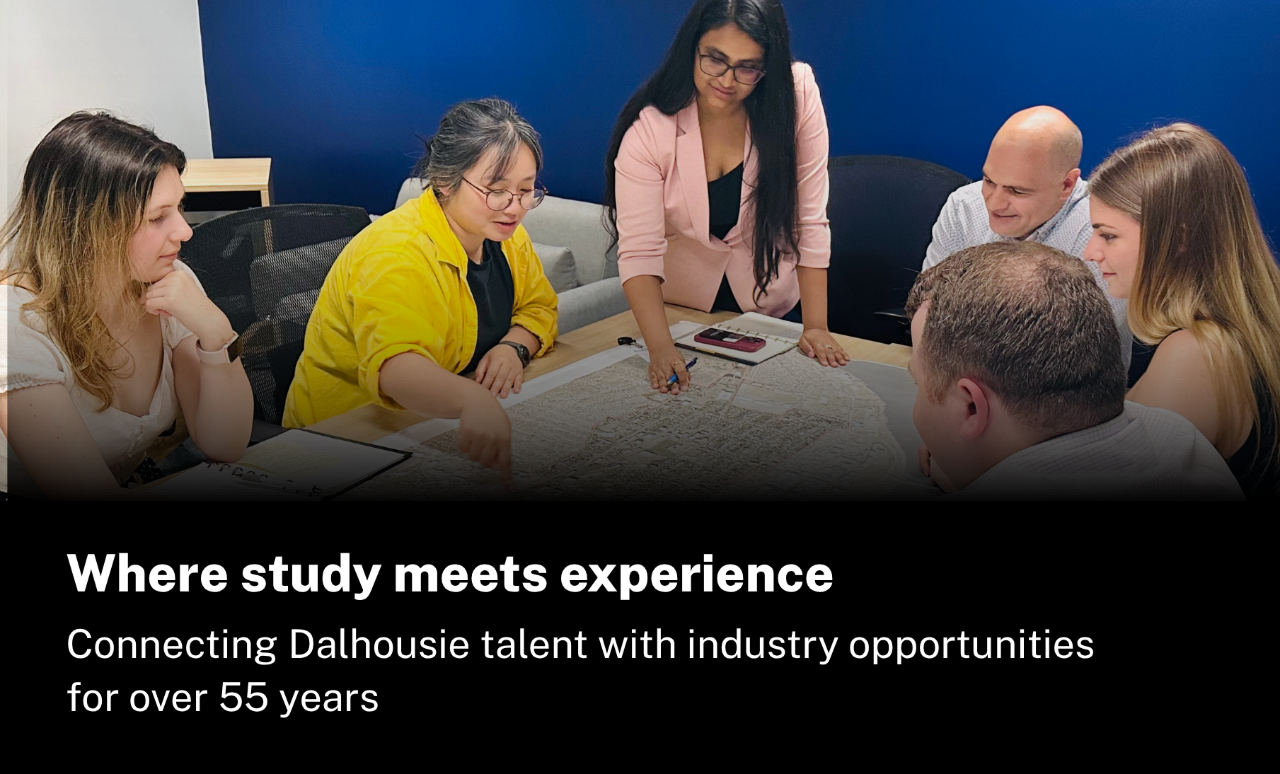 A group sitting around a boardroom. They are looking at a map on the table.