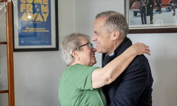 Prime Minister Mark Carney gets a hug from Beulah Cooper as he arrives at her house in Gander, N.L., on March 24, 2025. Cooper housed Americans during 9/11 and is featured in the musical Come From Away. (THE CANADIAN PRESS/Frank Gunn) Prime Minister Mark Carney gets a hug from Beulah Cooper as he arrives at her house in Gander, N.L., on March 24, 2025. Cooper housed Americans during 9/11 and is featured in the musical Come From Away. (THE CANADIAN PRESS/Frank Gunn)