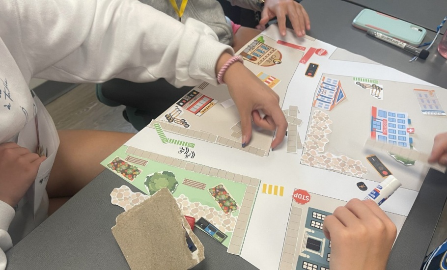 A group of children placing paper crosswalks, stopsigns, and sidewalks on a street map
