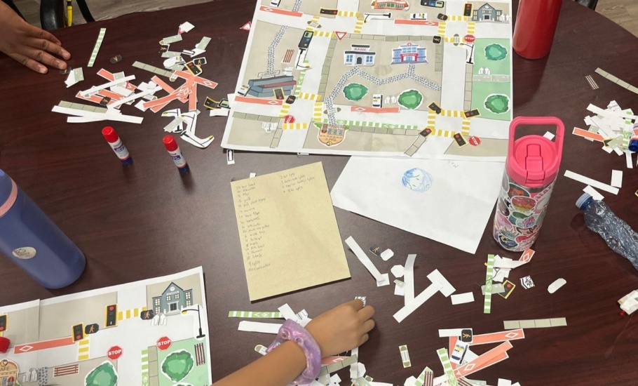Elementary school age children place paper infrastructure on an imaginary city block