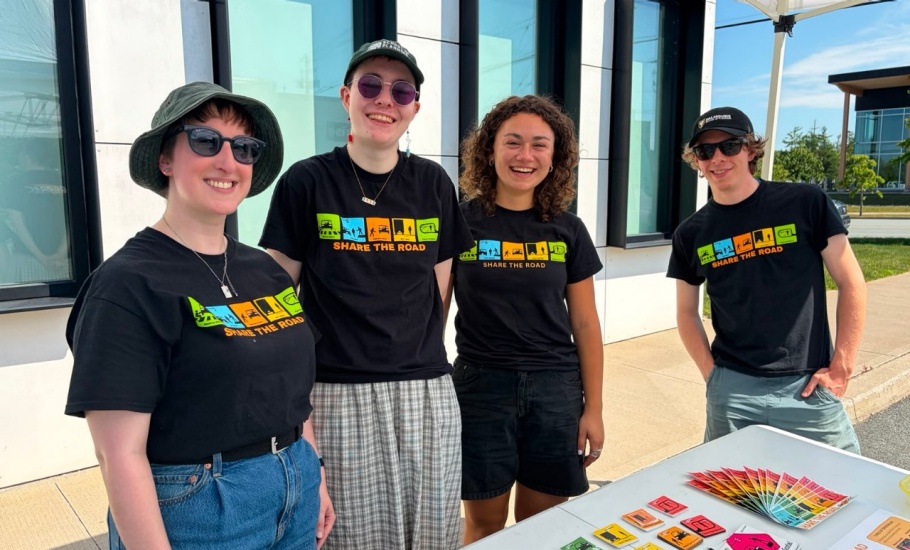 Jen, Zoe, Olivia, and Kieran standing behind the Share the Road booth at the 2026 Heartland Tour
