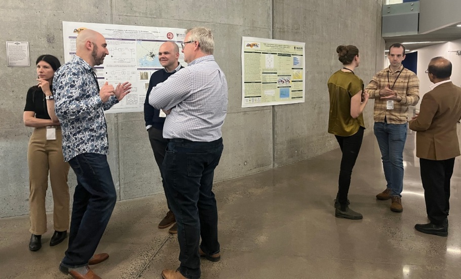 A group of people discussing research presented on posters