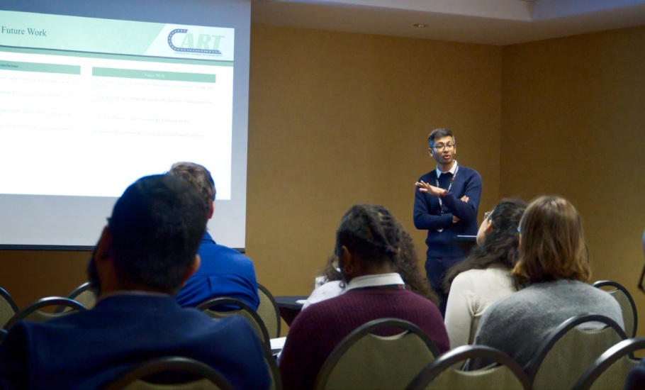 Azam talking infront of a slideshow presentation to a room of transportation professionals and researchers