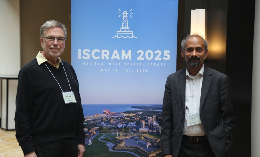 Two men standing in front of the ISCRAM 2025 Halifax banner