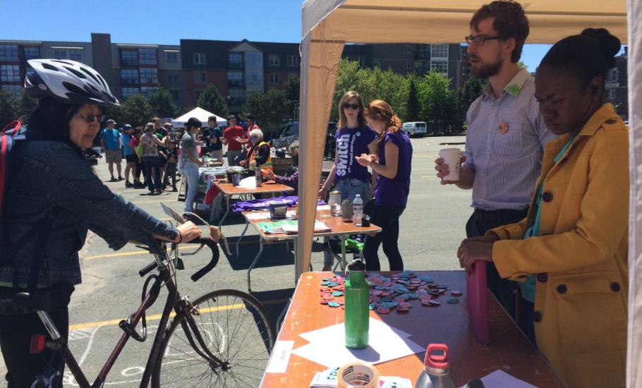 Two people standing at a table discussing the share the road campaign with a visitor