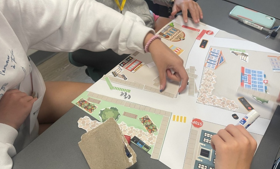 Middle school students create an imaginary road using paper pieces on a map