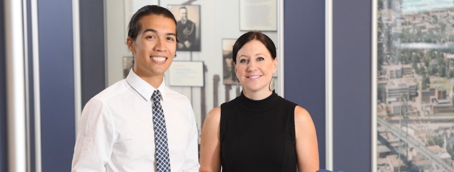 Two students in a government office smile at the camera.